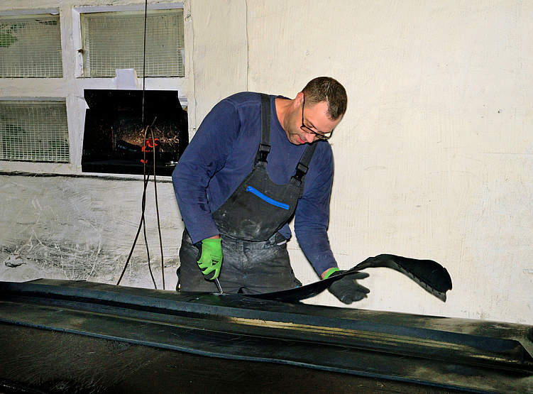 Mitarbeiter Christian Ruhe schneidet Gummi­platten. Diese werden später für Bahnübergänge genutzt. Foto: Peer Hilbert